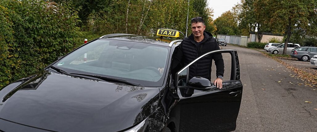 Taxi-Fahrer öffnet Tür für Fahrgast – Flughafentransfer Stuttgart STR mit Festpreis